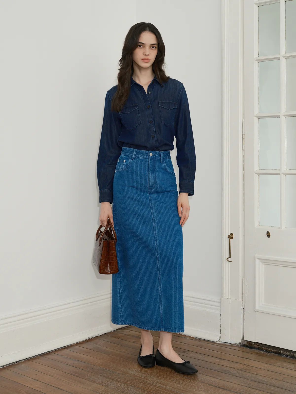 Andreatang CINDY lyocell cotton denim slim fit shirt styled with blue denim midi skirt, white wall background, minimalist fashion