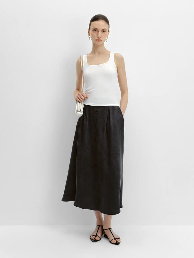 Front view of black NOBU Midi Skirt with white tank top, silver earrings, and mini shoulder bag