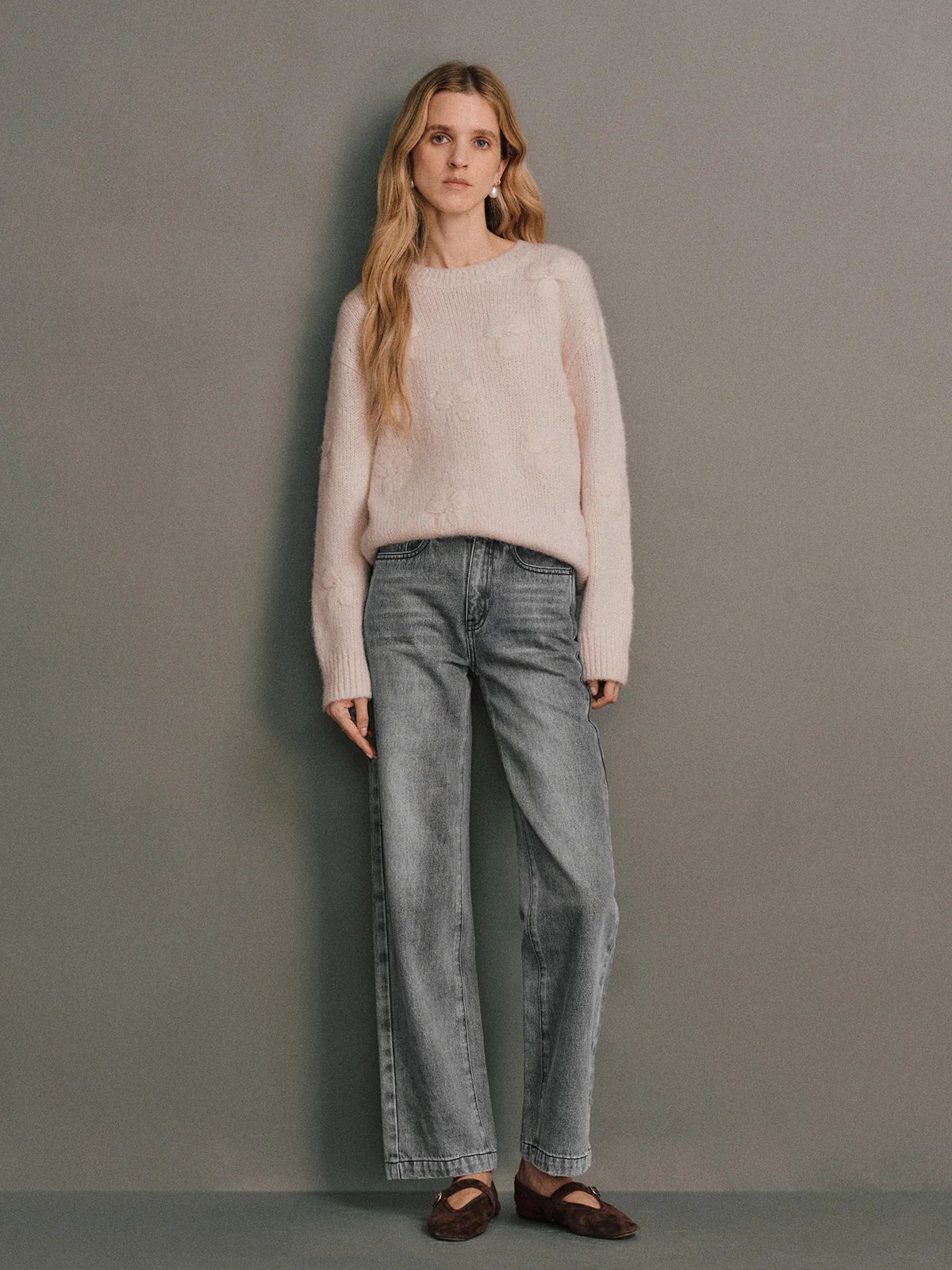 Front view of a model wearing a Pink alpaca wool embroidered jumper with wide-leg jeans and dark loafers.