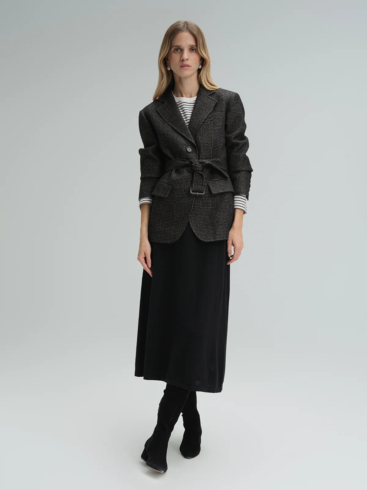 Model in andreatang houndstooth belted blazer over striped top and black midi skirt