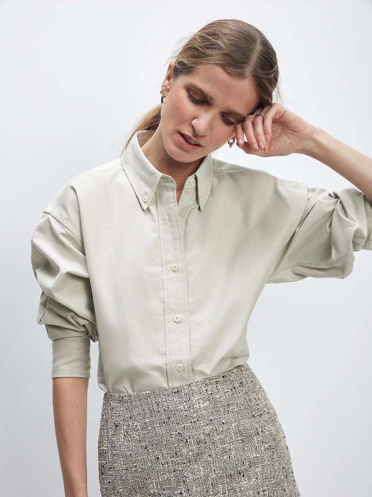 Front view of a model in a loose Slate Gray Oxford shirt with voluminous sleeves, styled with a tweed mini skirt and loafers.