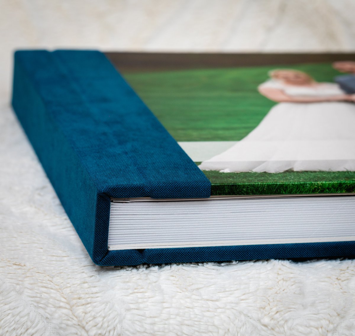 Blue textile wedding album lying closed on its side, showing the thick block of lay-flat pages.