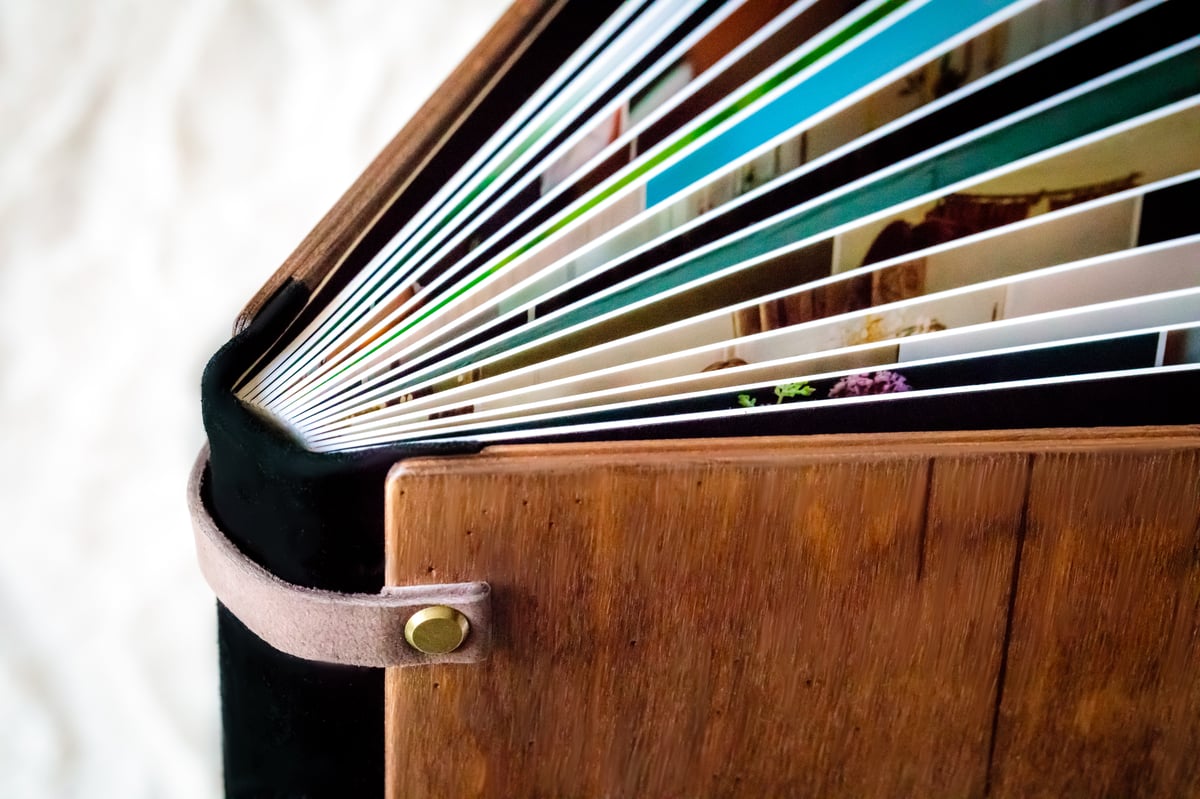 Close-up of the wooden album&rsquo;s fanned lay-flat pages.