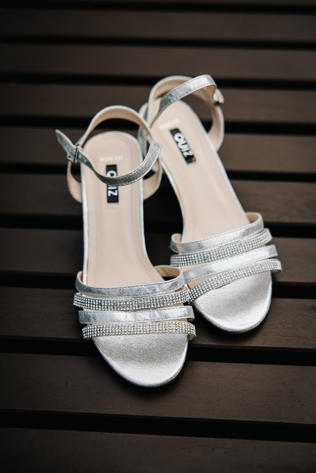 Silver diamante strappy sandals resting on dark timber boards