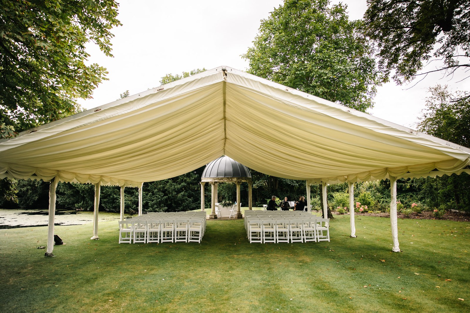An open-sided marquee set with rows of white chairs on the lawn at Ardington House