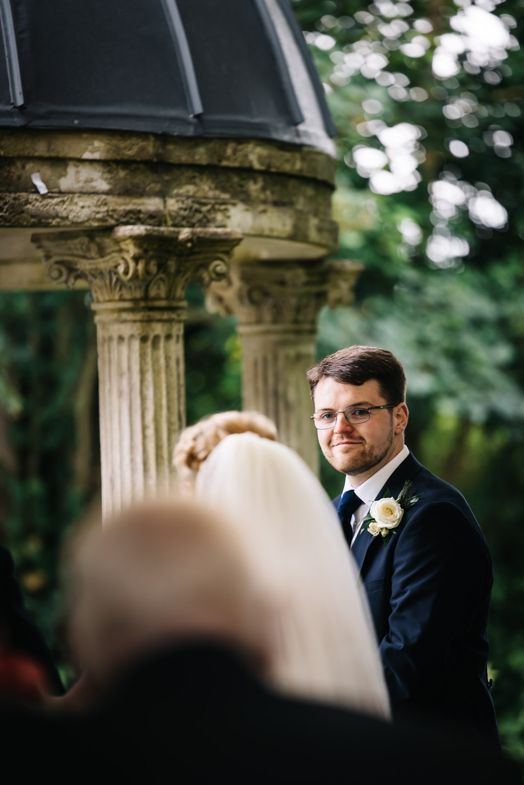 The groom waiting at the stone temple, moved as the bride approaches