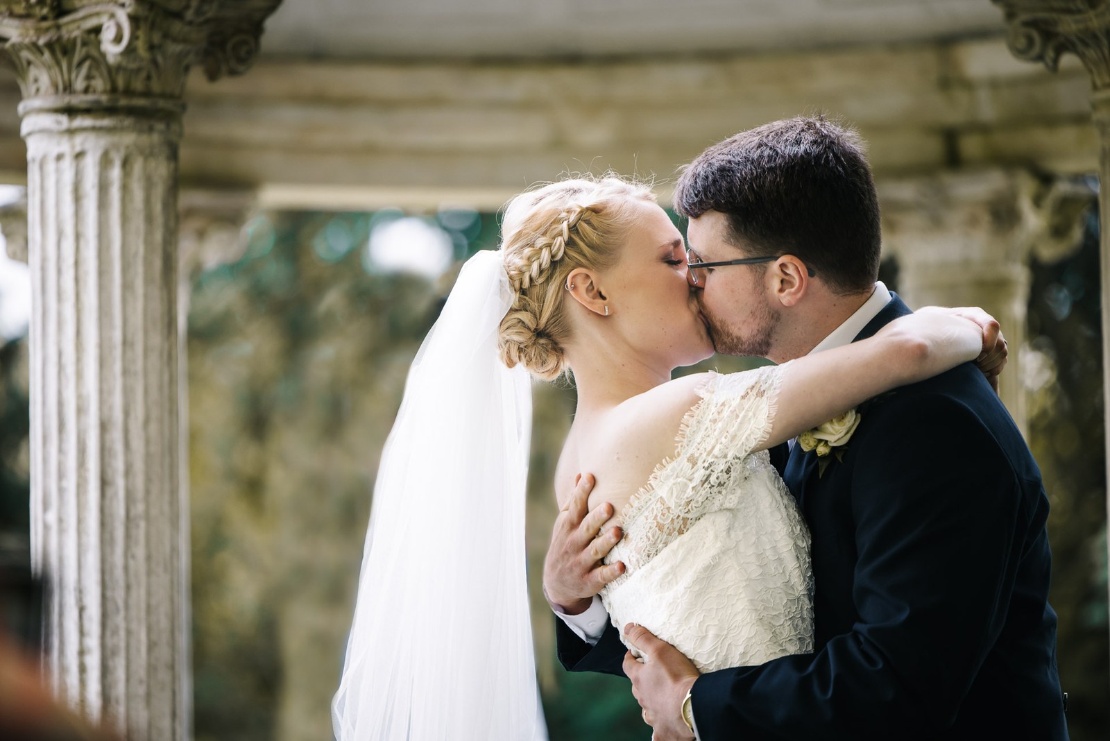 The couple sharing their first kiss beneath the temple's stone columns