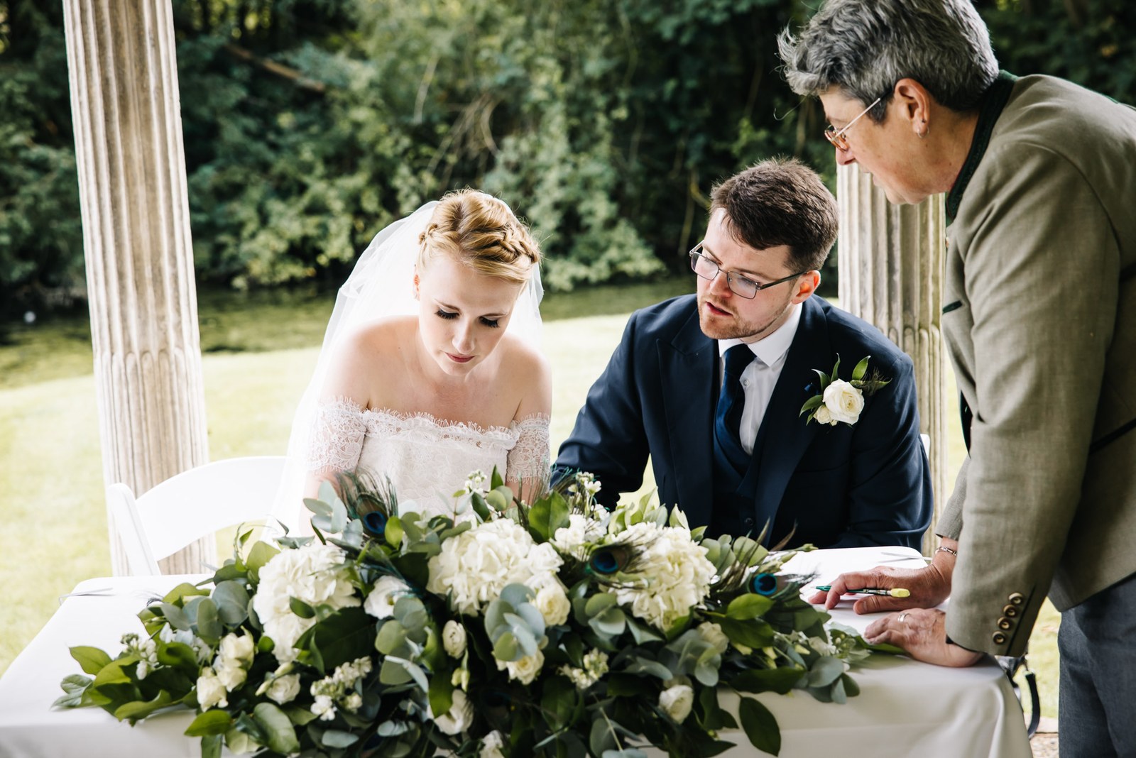 Signing the register at a flower-dressed table as the registrar looks on