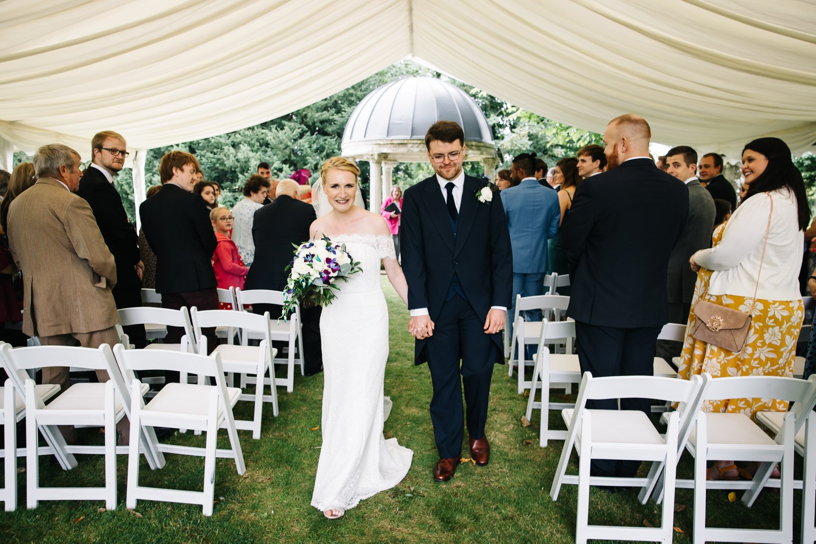 Bride and groom walking back down the aisle through the marquee