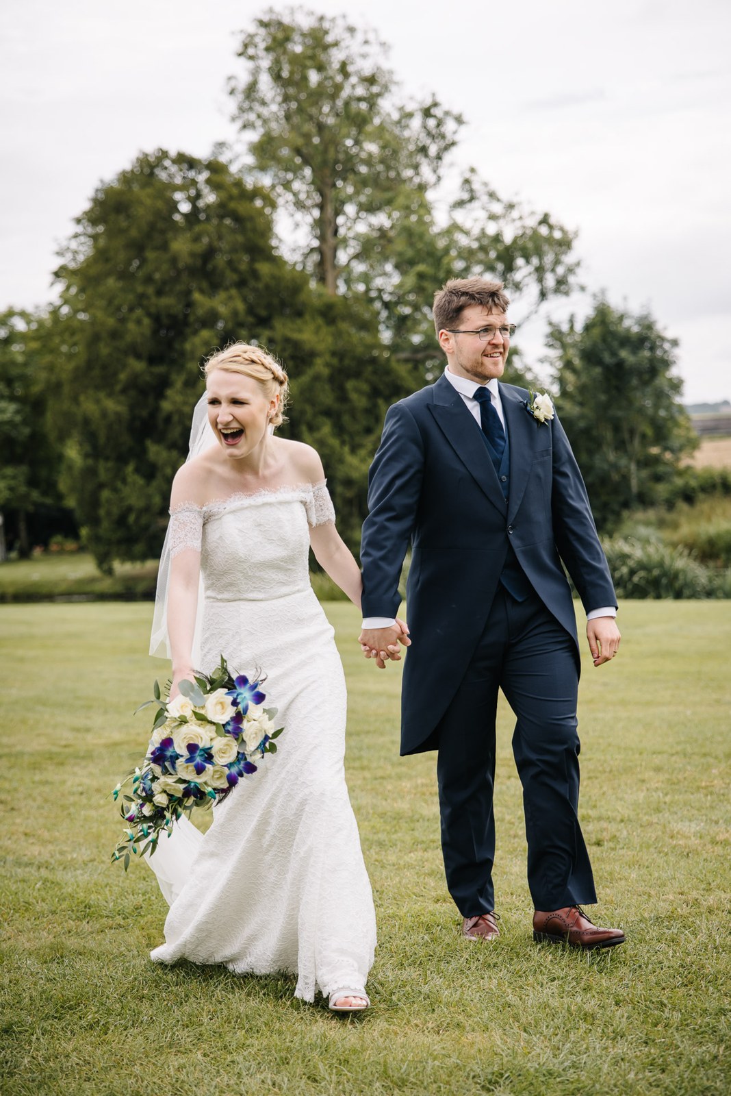 The laughing couple strolling across the lawn with open countryside beyond