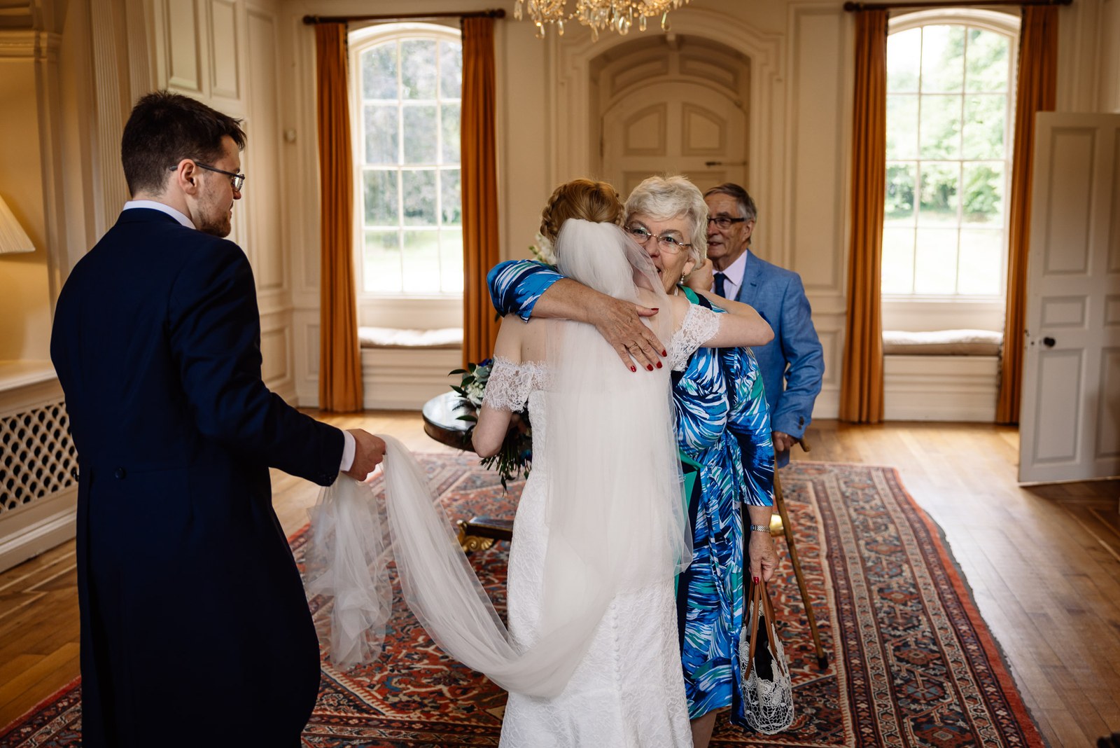 The bride embracing an older guest in a panelled room at Ardington House, an oriental rug underfoot