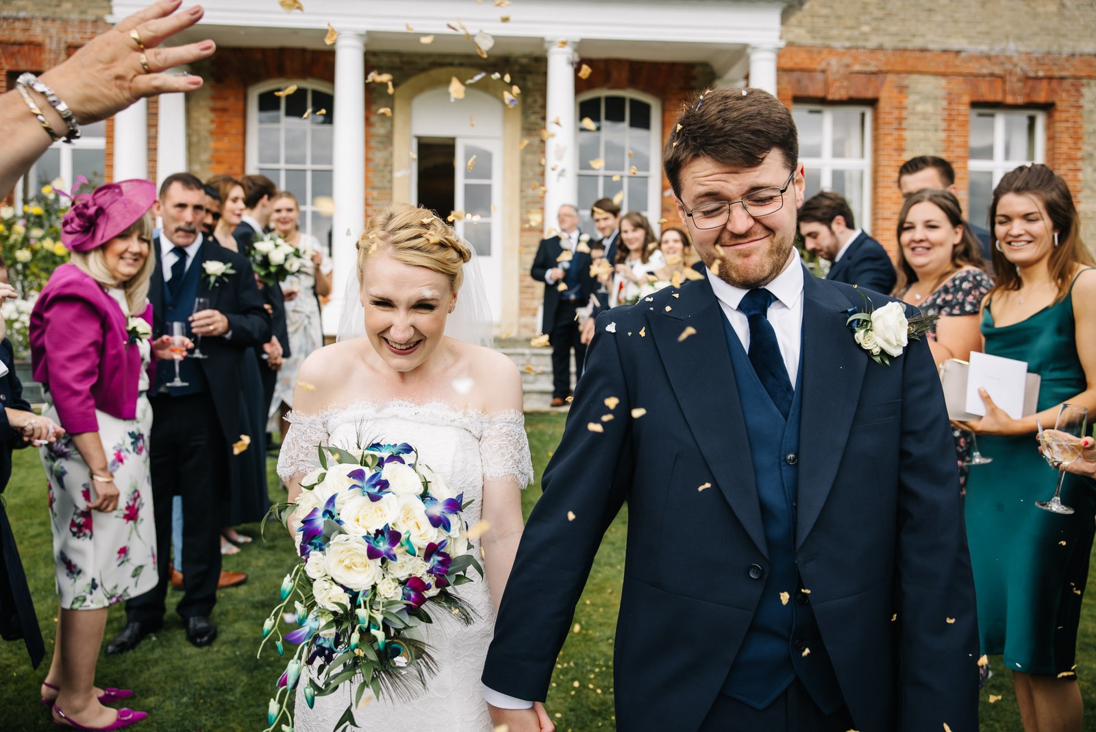 Confetti showering over the couple outside the entrance to Ardington House