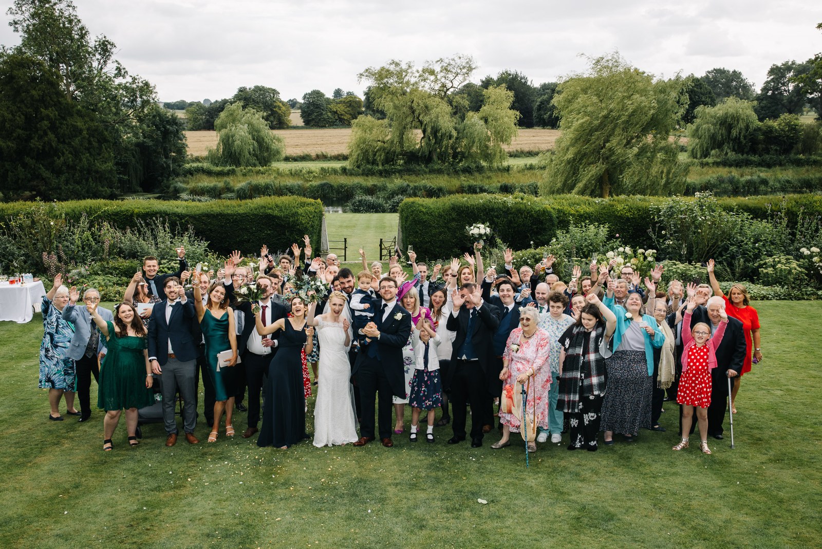 A large group portrait of every guest on the lawn at Ardington House, countryside beyond