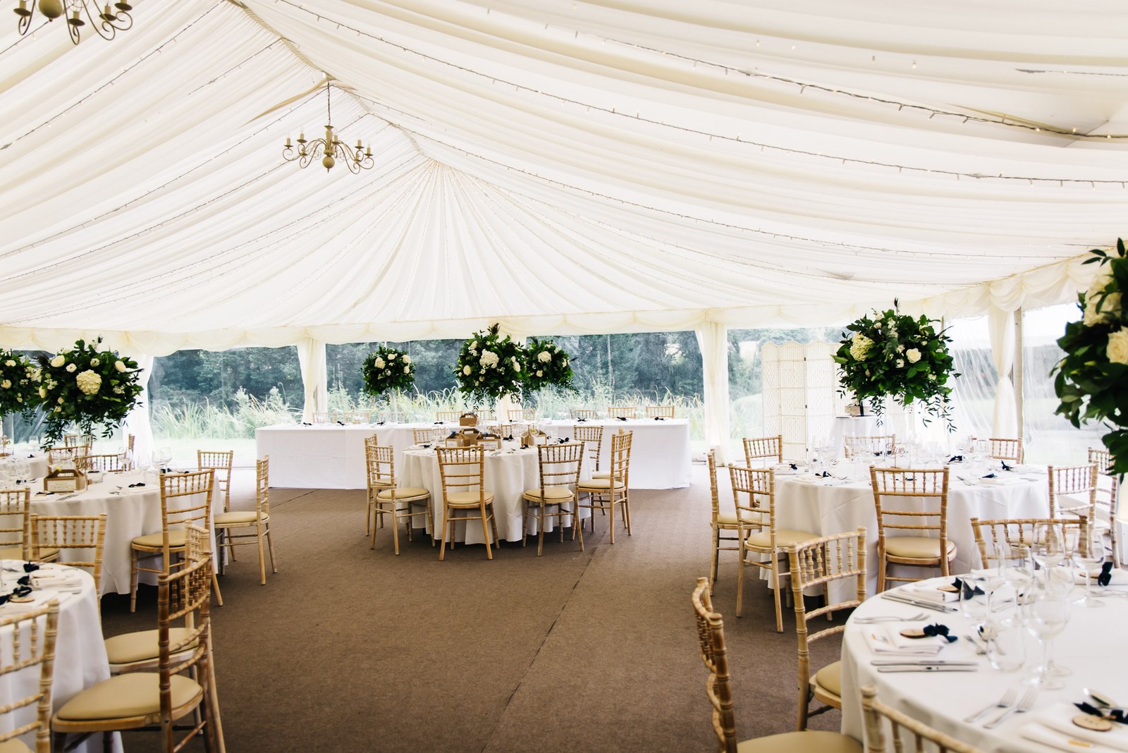 The reception marquee at Ardington House laid with round tables and floral centrepieces