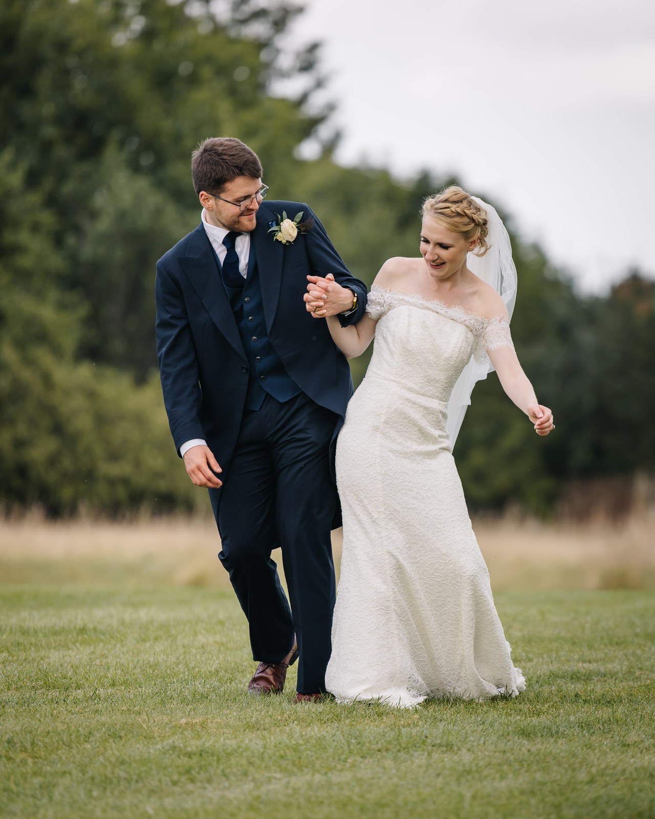 Bride and groom walking together across the striped lawn