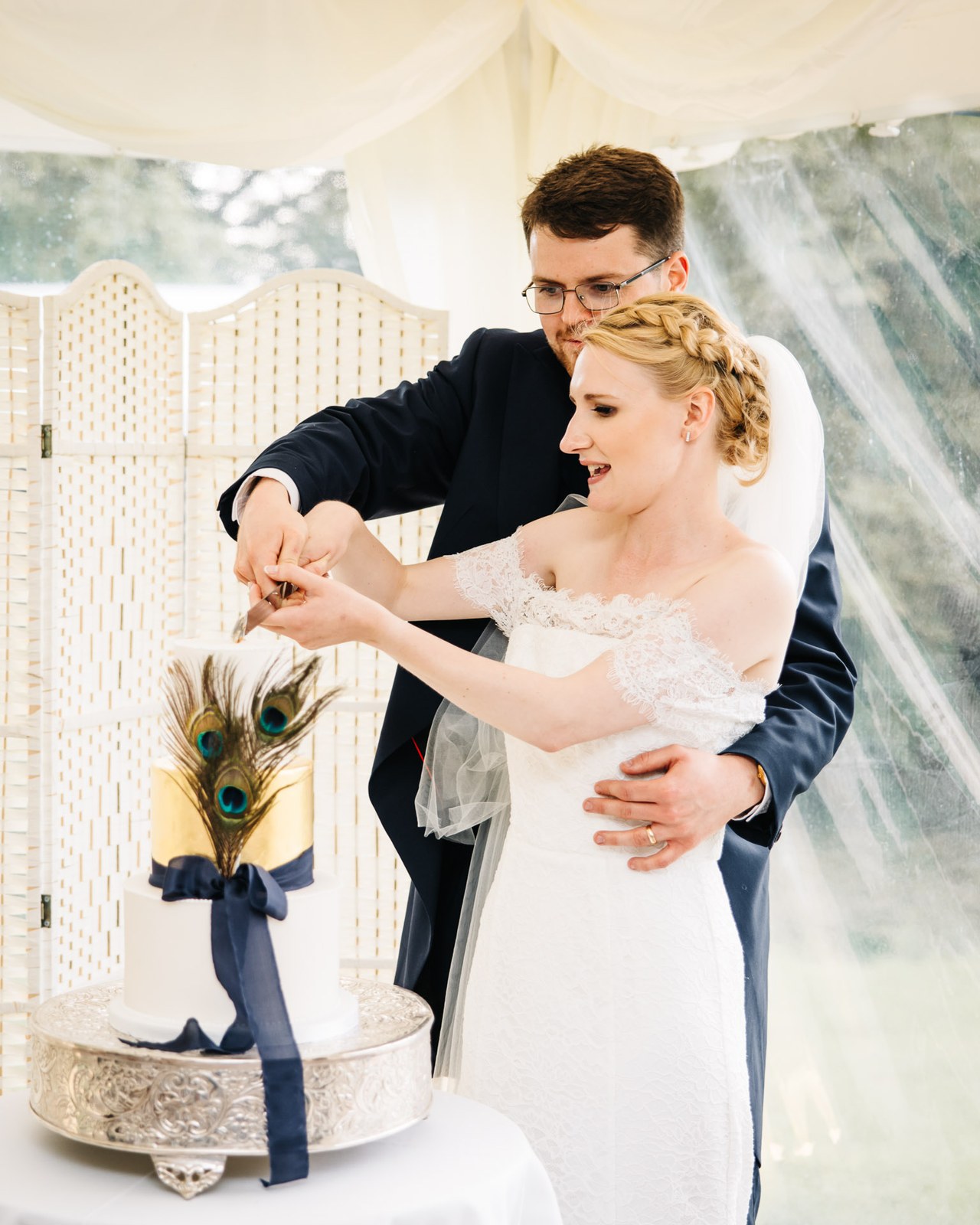 The newlyweds cutting their peacock-feather cake together