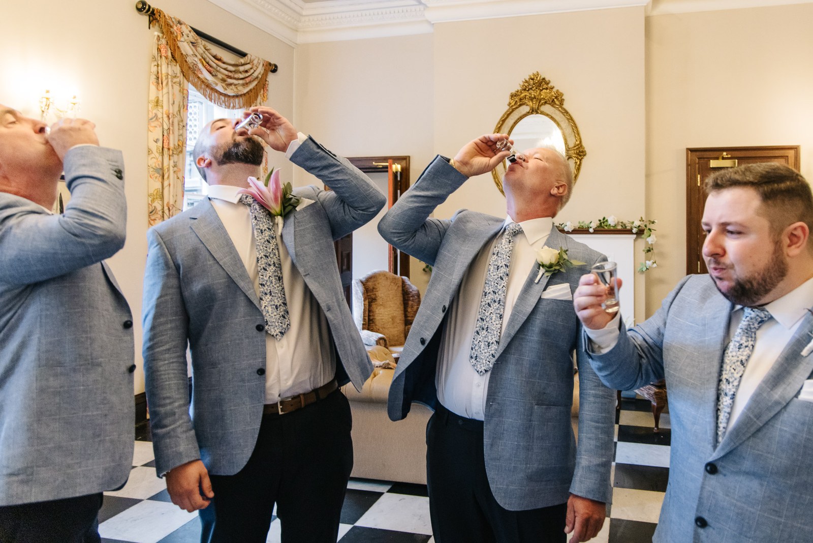 The groom and his groomsmen downing shots on a chequered floor
