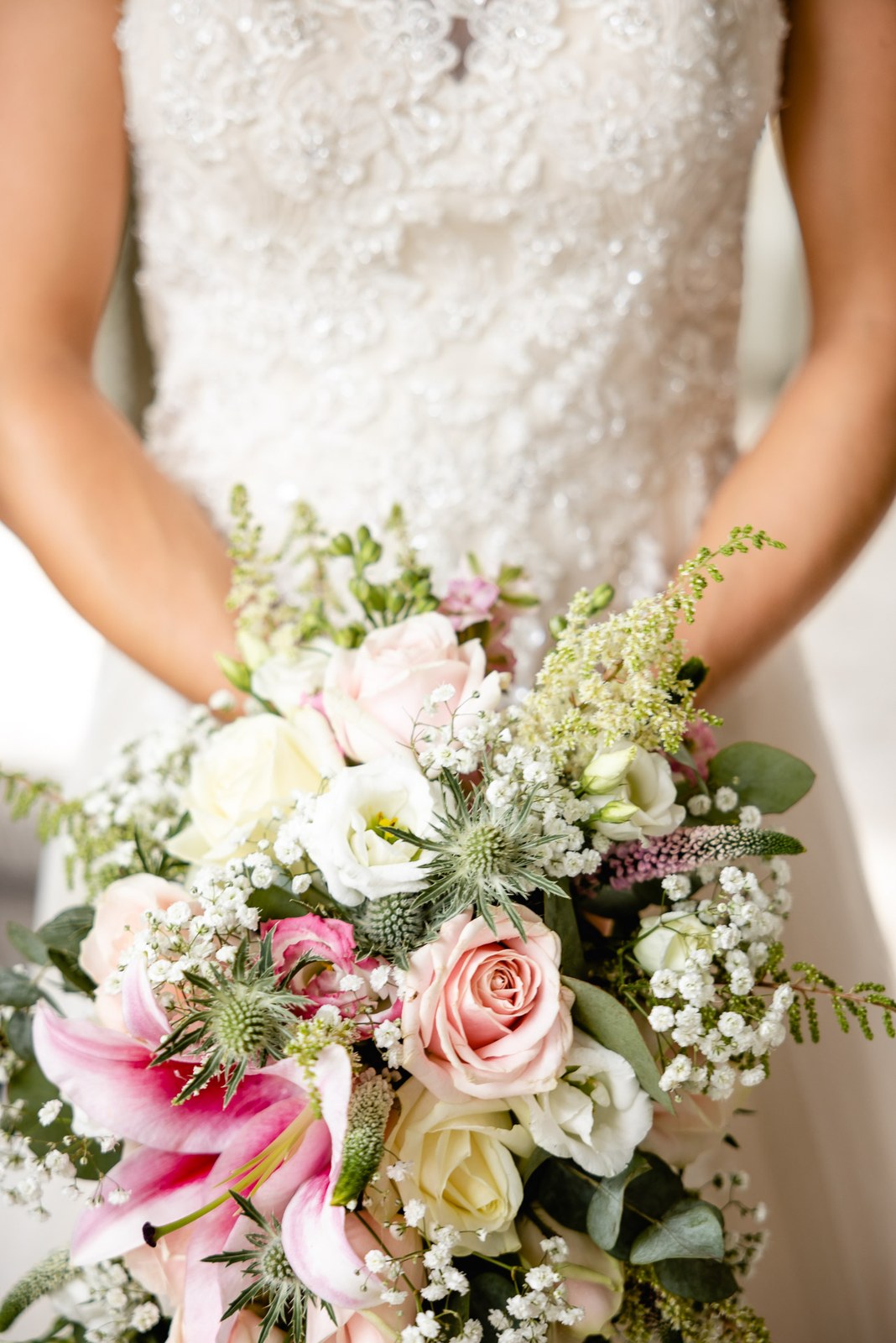 Close-up of the bride's bouquet of pink roses, lilies, thistles and gypsophila