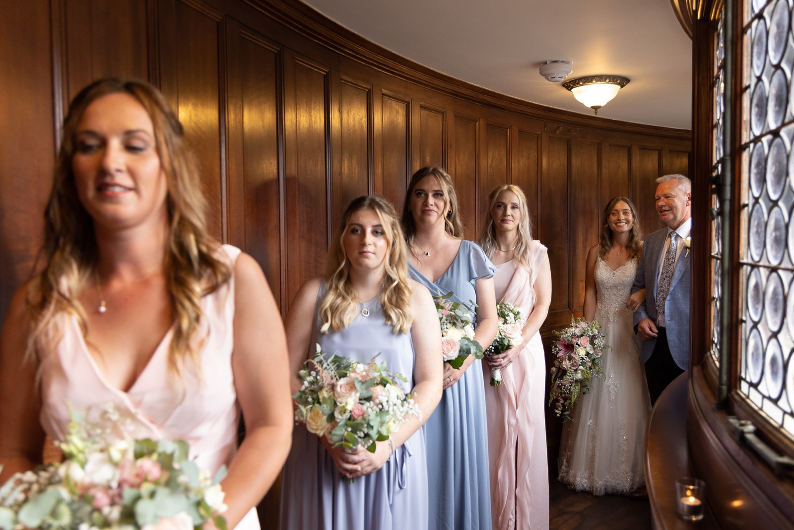 The bride and her bridesmaids lined up in the panelled hall before the ceremony