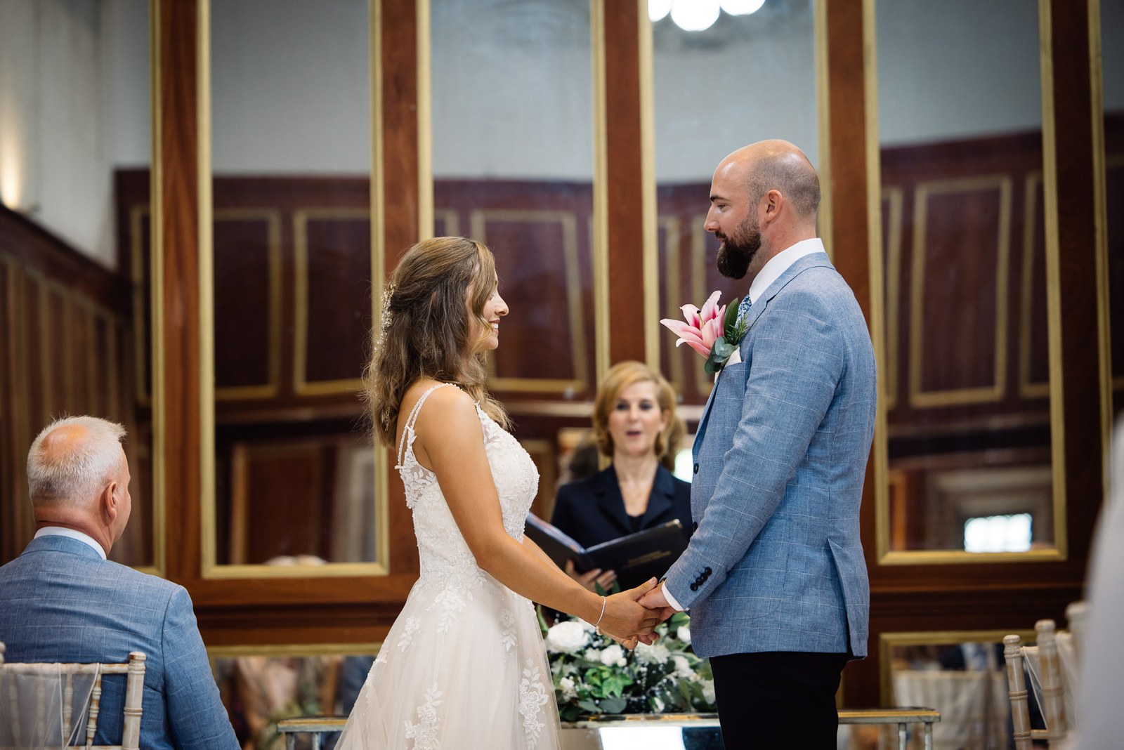 Bride and groom holding hands during their vows in the panelled room