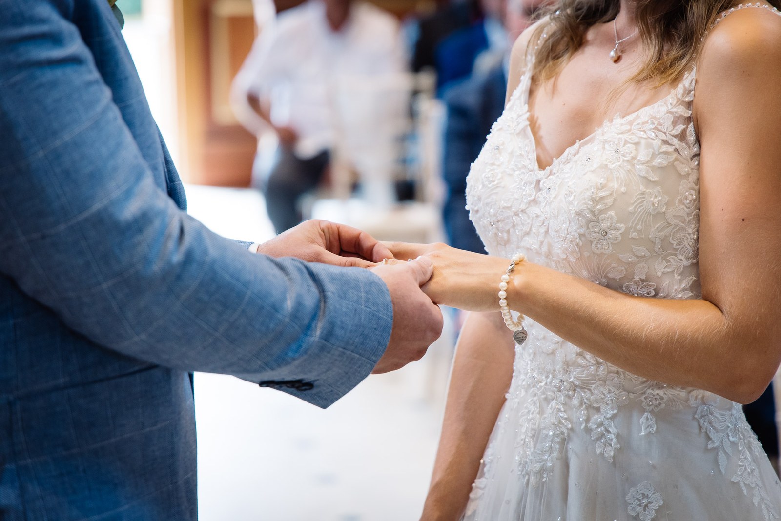 The groom sliding the wedding ring onto the bride's finger