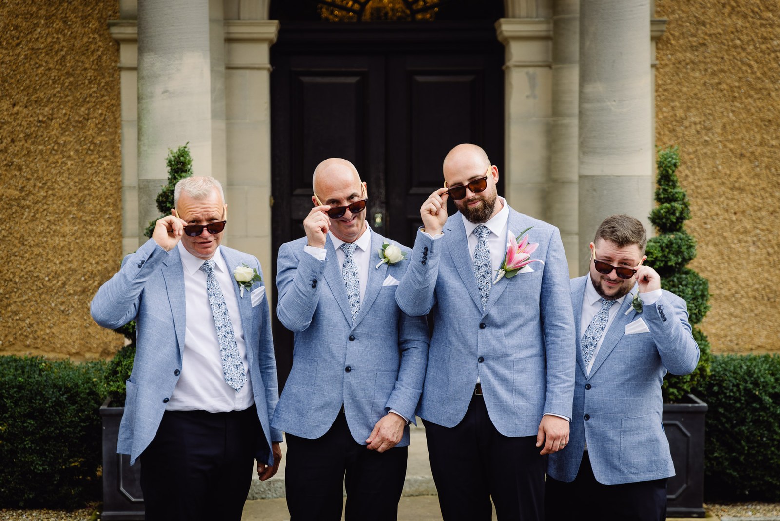 The groom and groomsmen lowering their sunglasses outside the entrance
