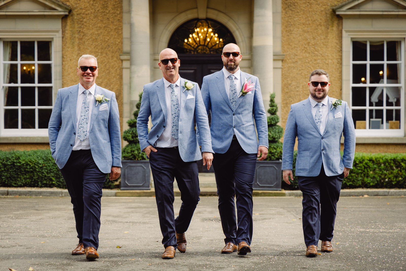 The groom striding toward camera with his groomsmen in pale blue jackets