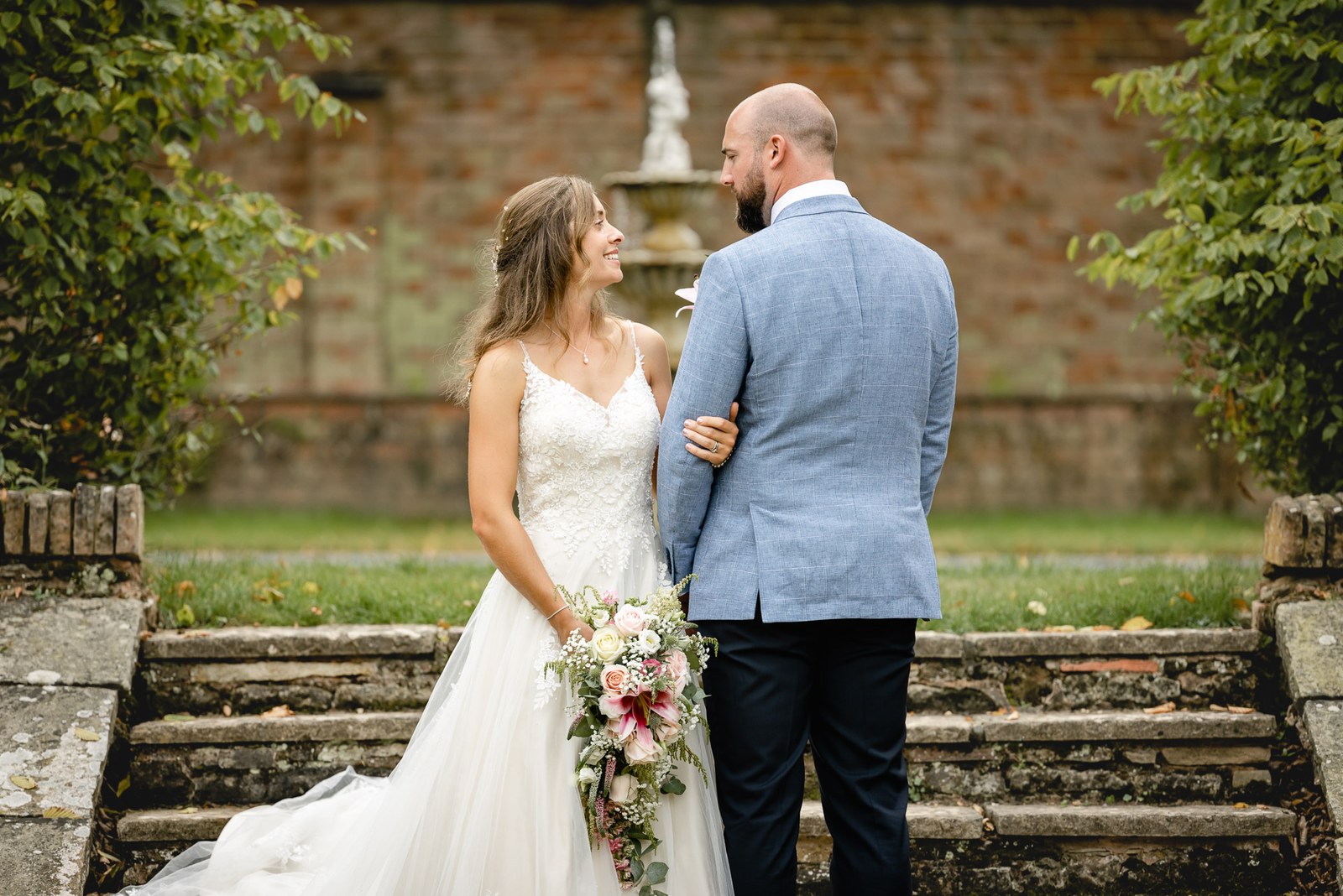 The couple beside a garden fountain and stone steps