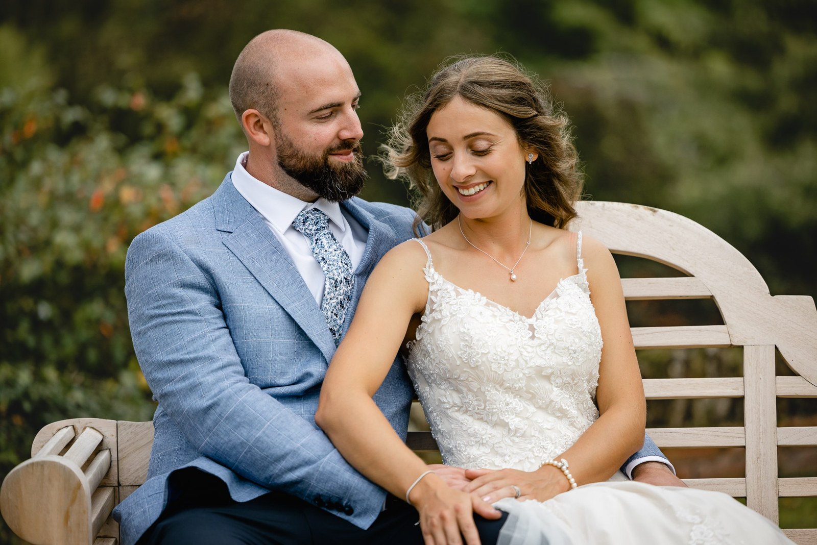 The couple sitting close together on a wooden garden bench