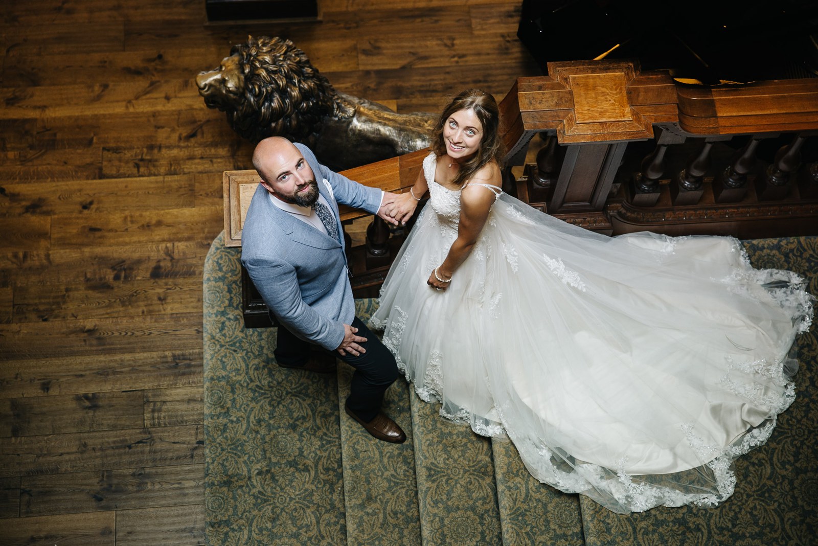 The couple by a carved lion sculpture in a wood-panelled room at Bourton Hall