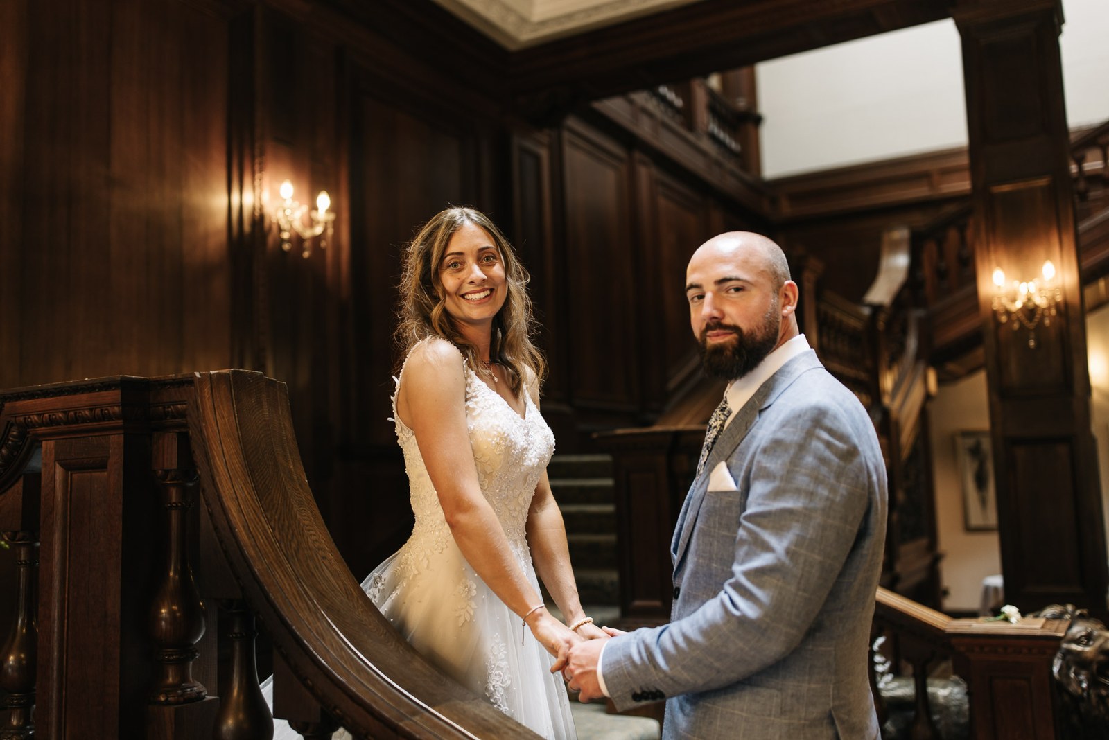 Bride and groom holding hands at the foot of the grand staircase