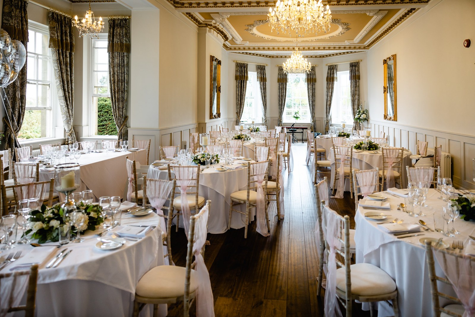 The reception dining room at Bourton Hall laid with round tables and a chandelier