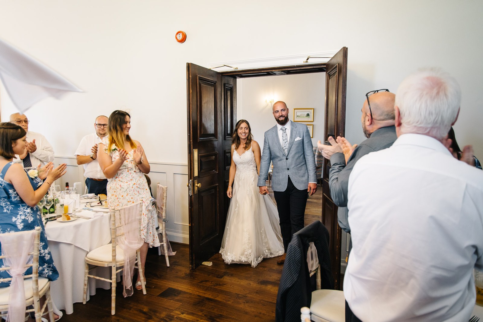 The newlyweds entering the reception as guests rise to applaud