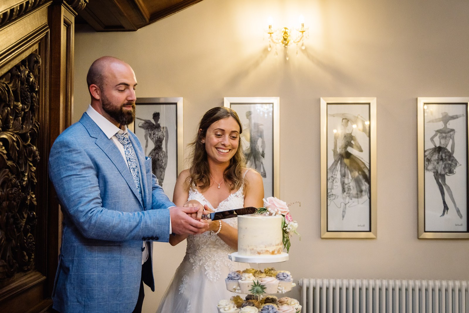 The couple cutting their semi-naked cake dressed with a pink rose