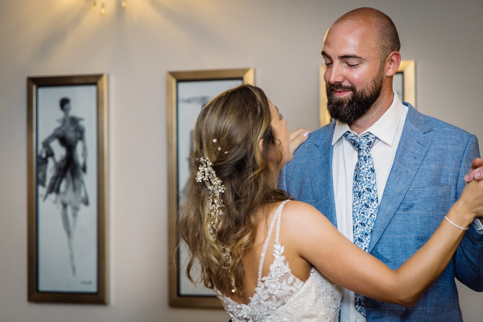 Bride and groom slow dancing before framed fashion prints