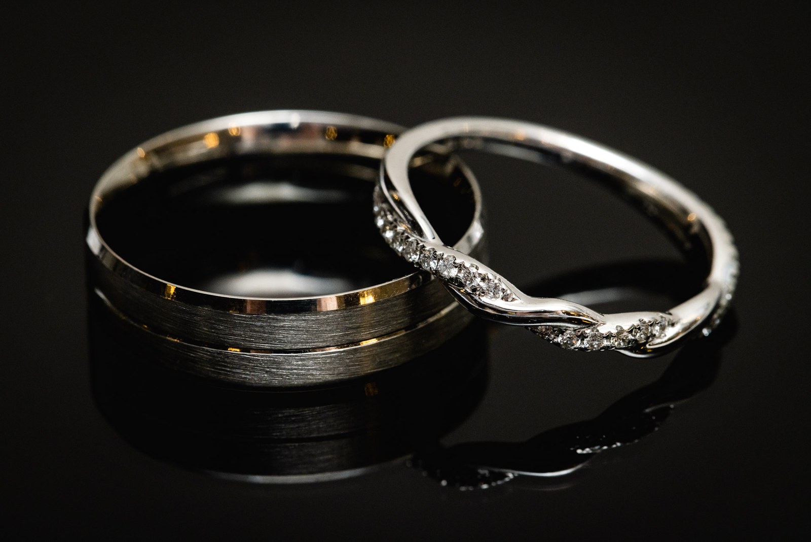 Close-up of a plain wedding band beside a diamond twist ring
