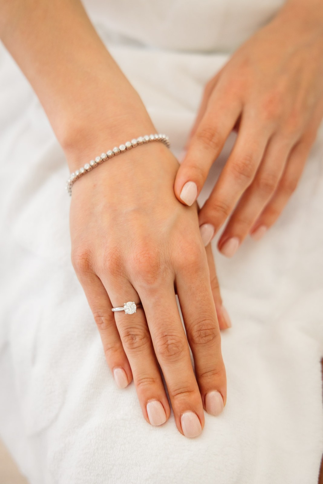 Close-up of the bride's hand showing her engagement ring and pearl bracelet