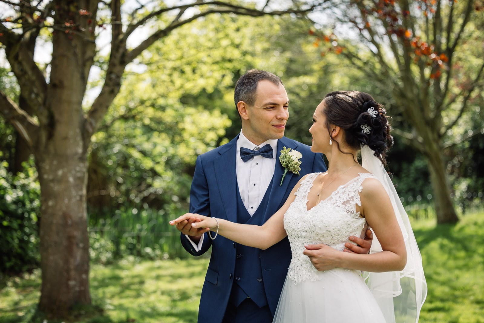 The couple embracing beneath the trees in the garden