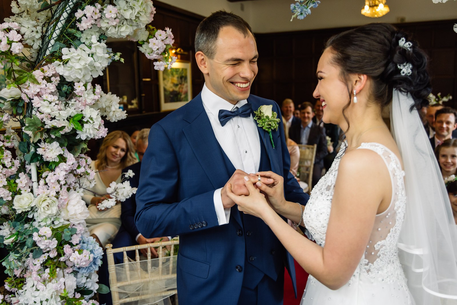 The couple exchanging rings under the flower arch