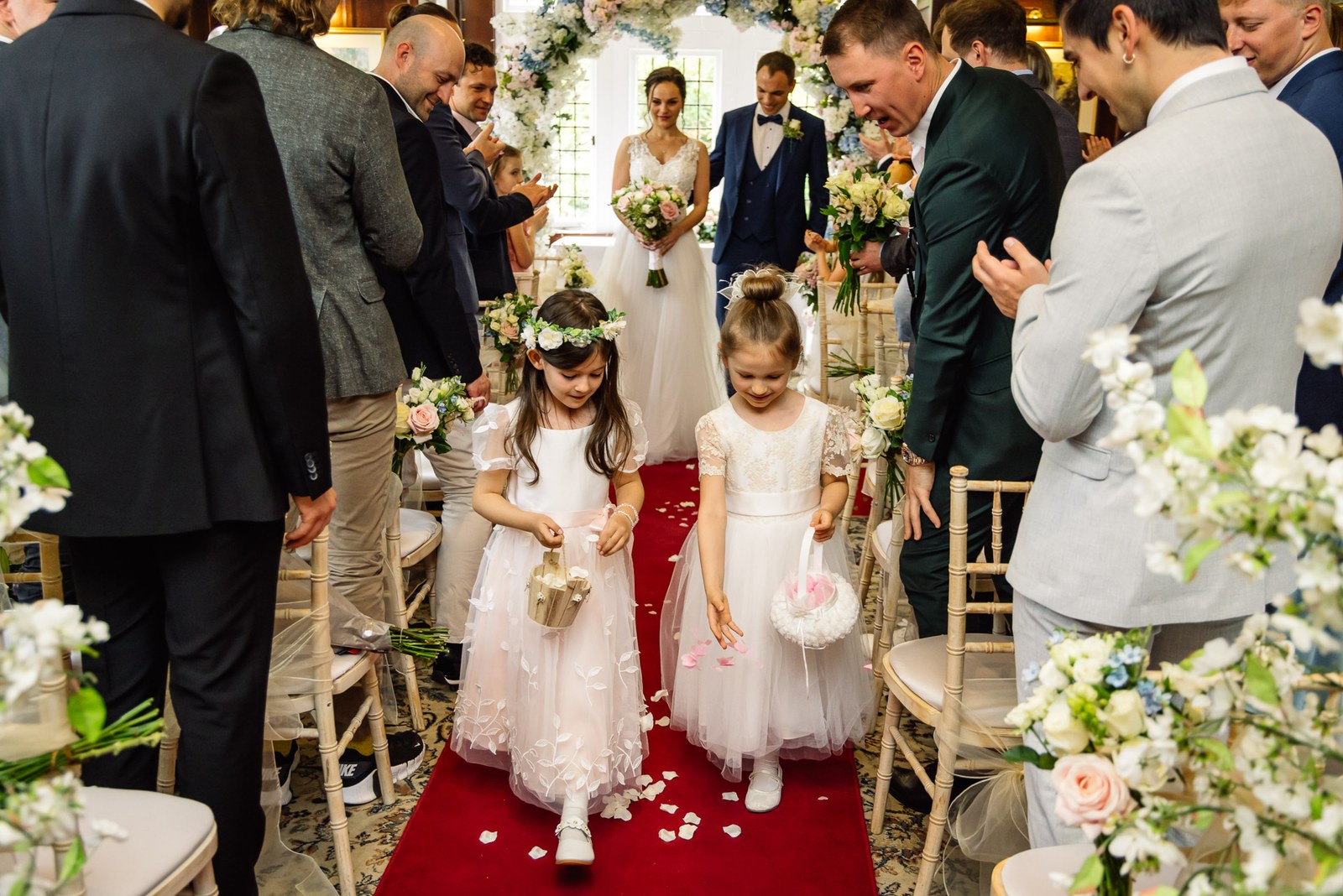 Two flower girls scattering petals down the red aisle