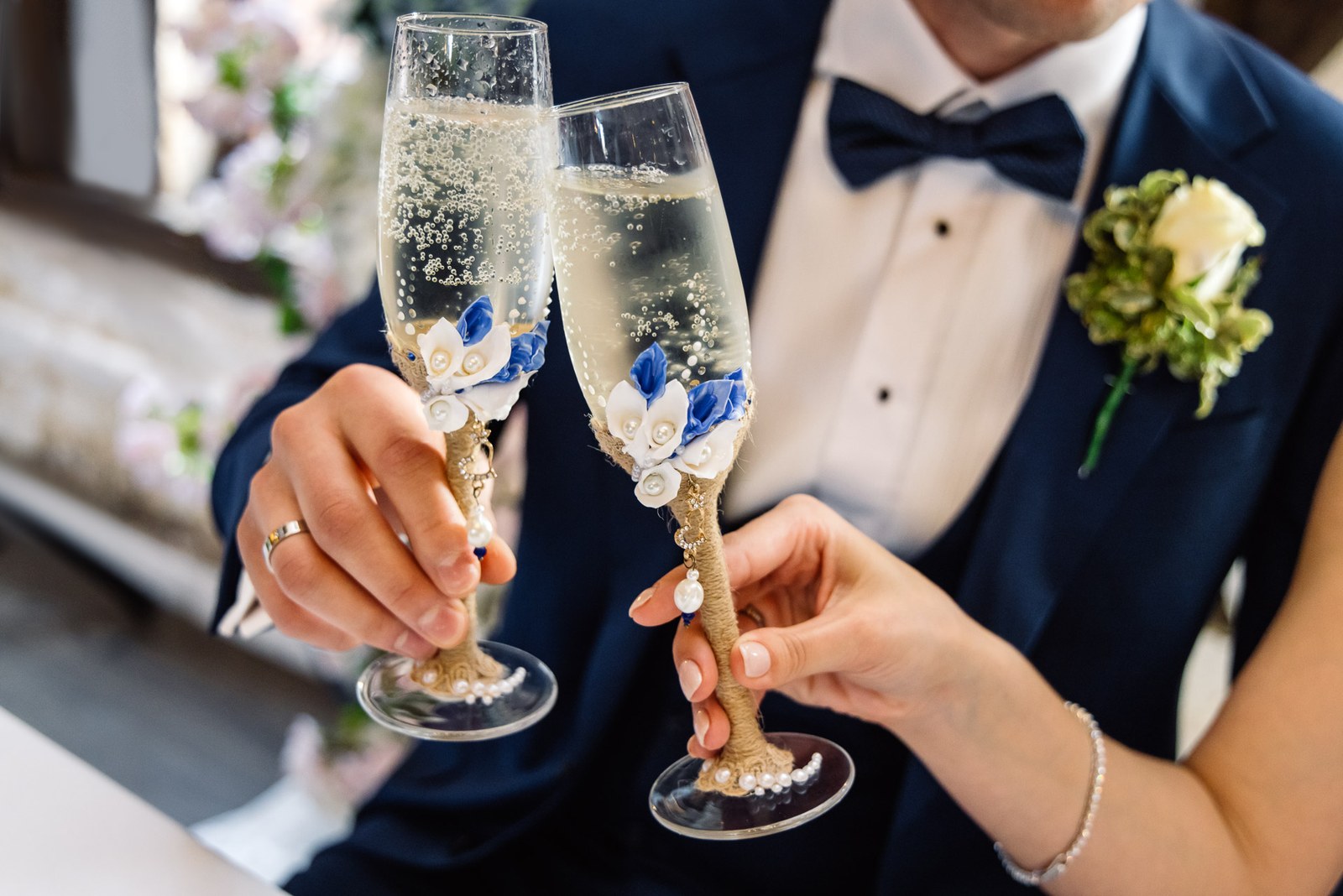 Close-up of the couple clinking decorated champagne flutes