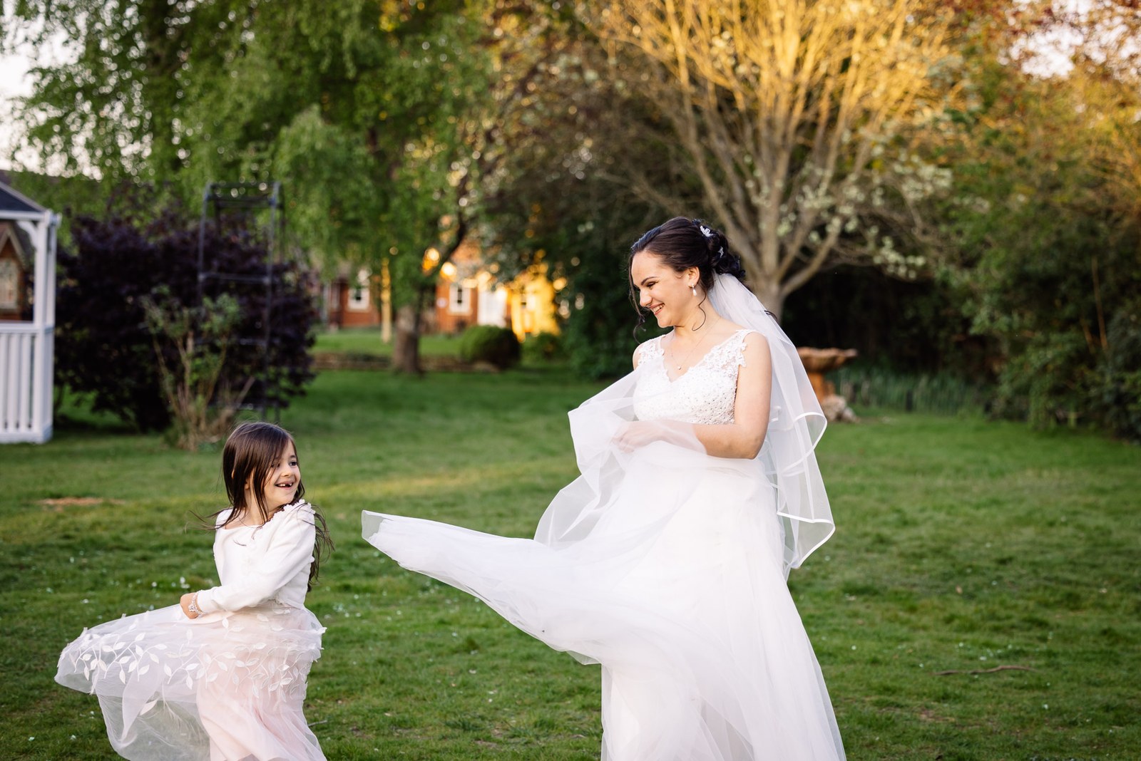The bride twirling her dress with a flower girl on the lawn at Cantley House Hotel
