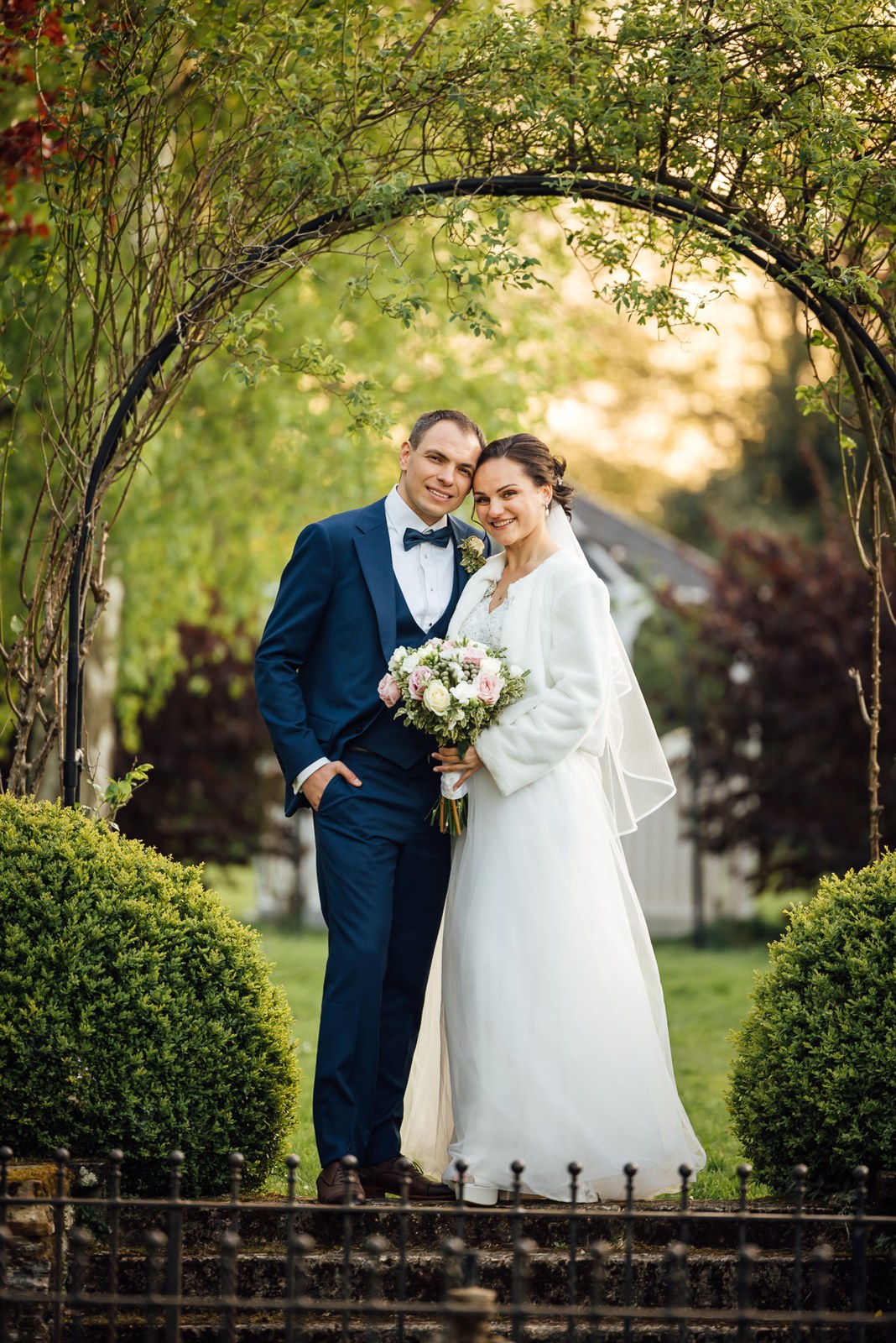 The couple framed by a leafy garden arch in the grounds of Cantley House Hotel