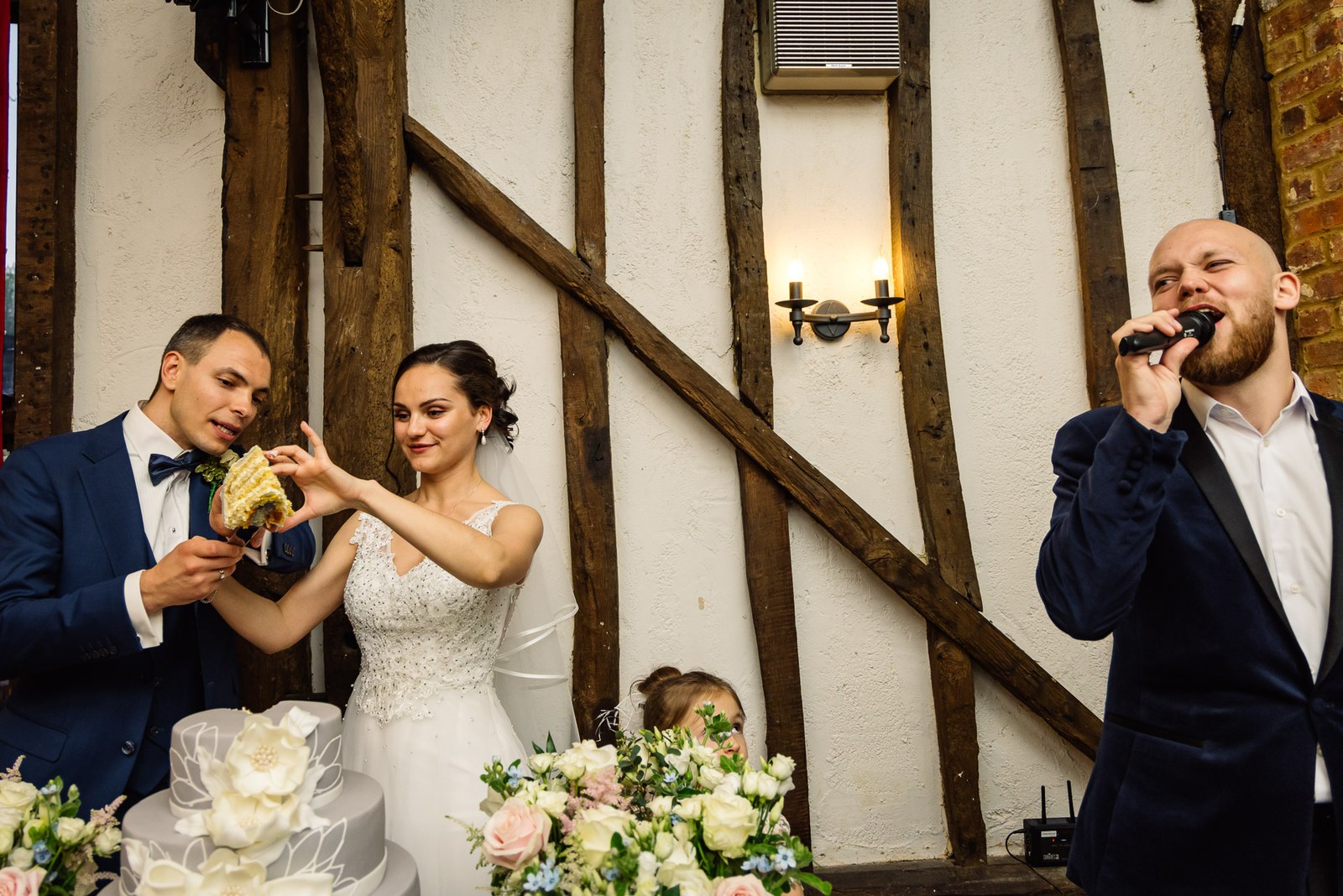 The bride feeding the groom cake as the MC sings into a microphone