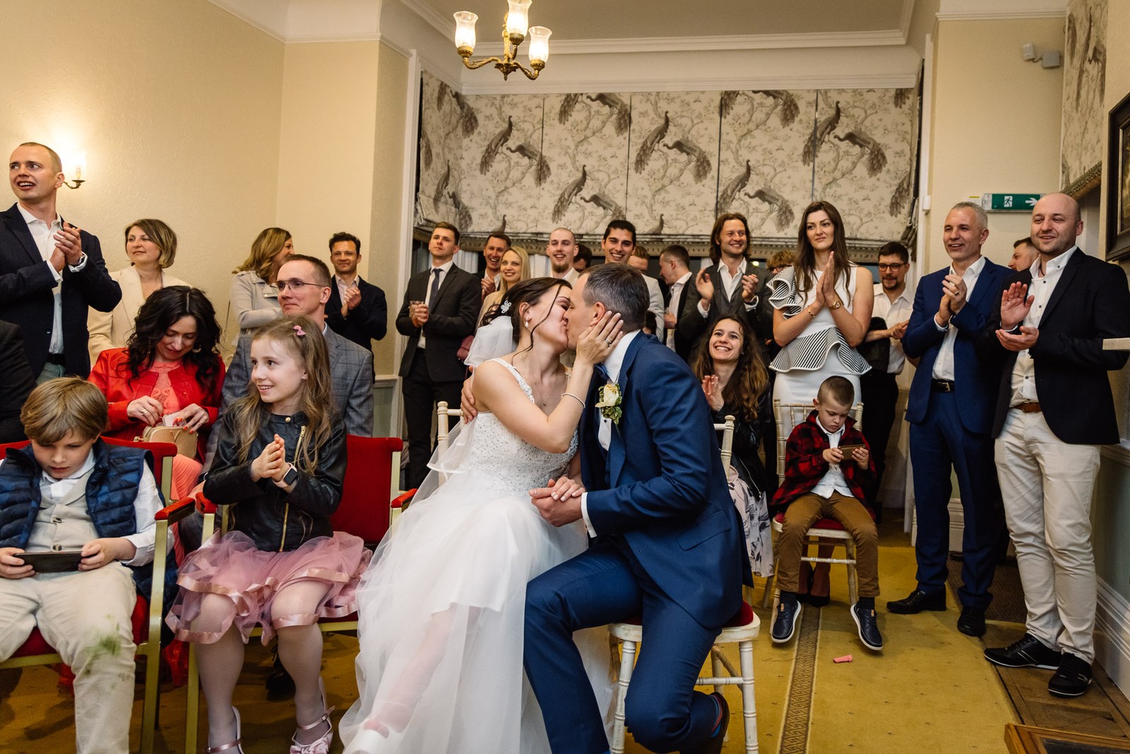 The couple kissing as guests clap around them