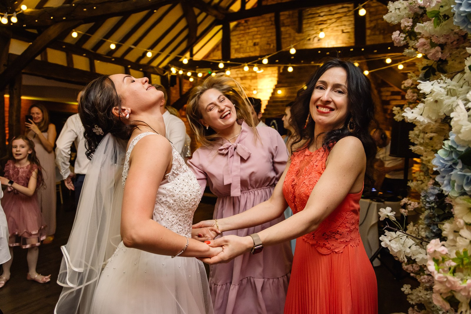 The bride dancing hand in hand with two women guests