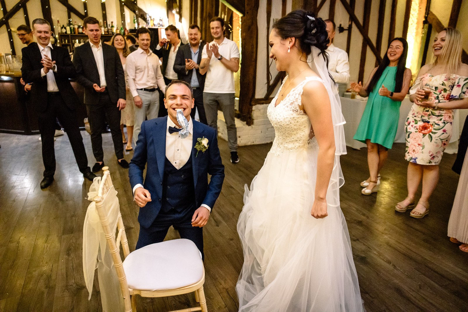 The groom beside a chair with the bride facing him during the reception games