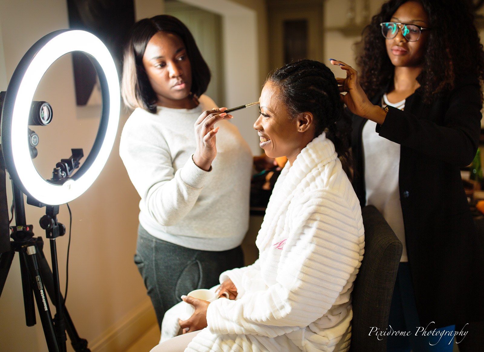Two stylists doing the bride's hair and makeup under a ring light