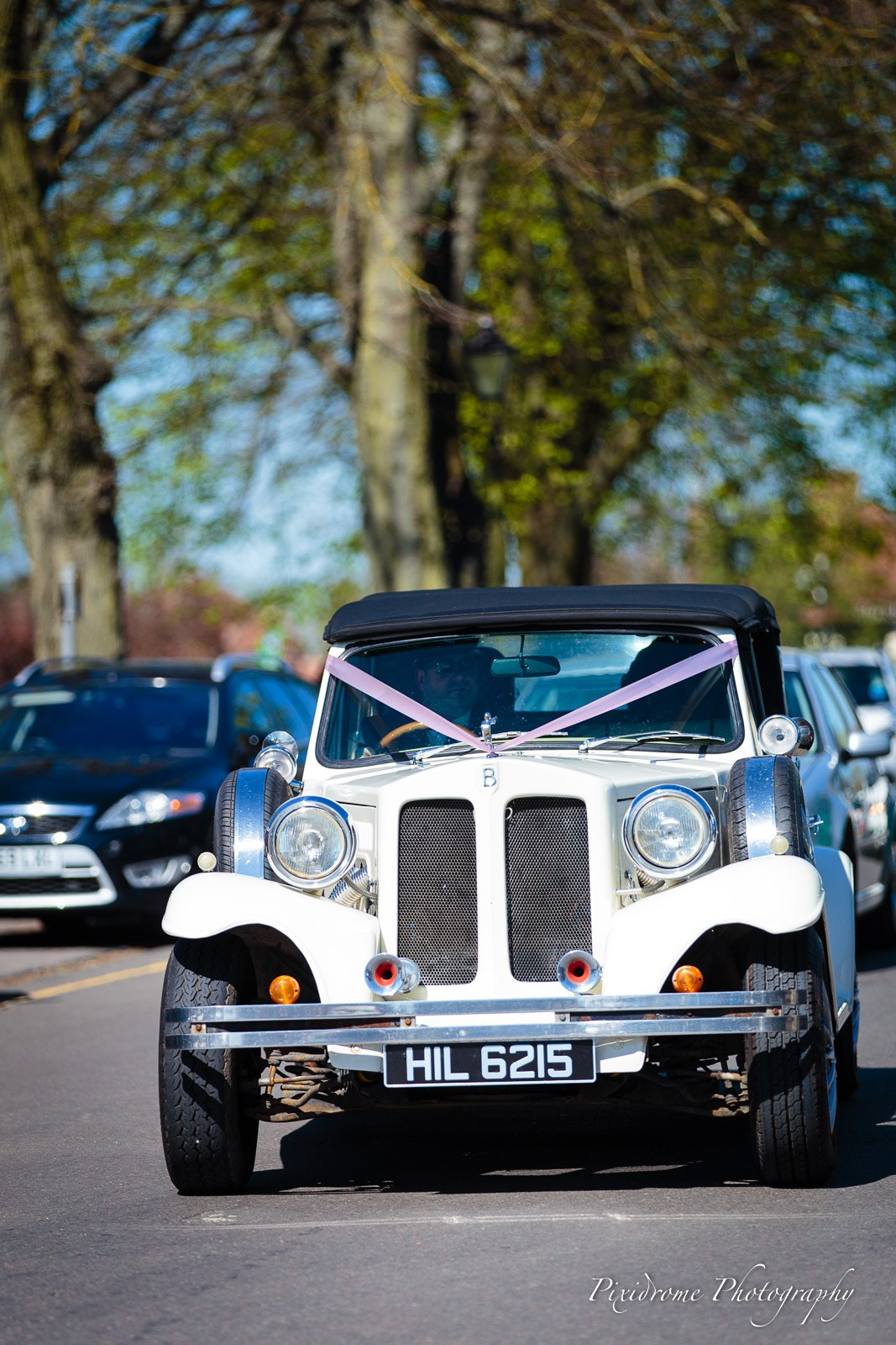 A ribboned vintage white wedding car waiting outside