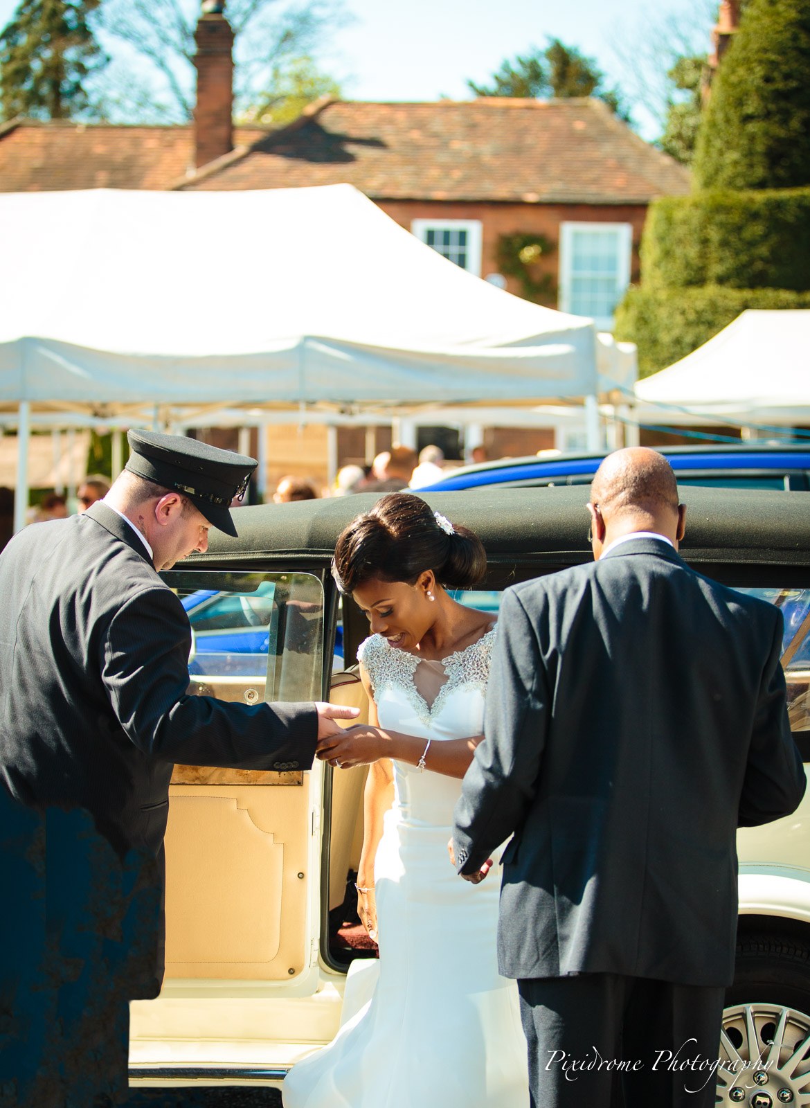 The chauffeur helping the bride step from the vintage car